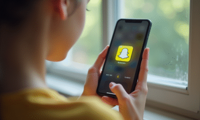 Jeune adulte tenant un smartphone avec Snapchat ouvert affichant un cœur jaune
