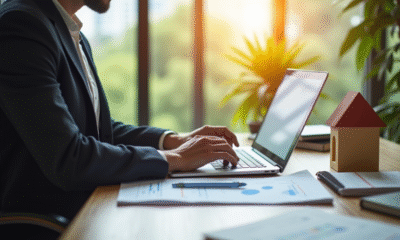 Personne examinant des documents immobiliers avec un ordinateur